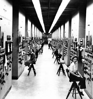 Operators and their control panels for calutrons (mass spectrometers for separating uranium isotopes) at the Y-12 site in Oak Ridge, Tennessee, USA. Photo © US Federal Government